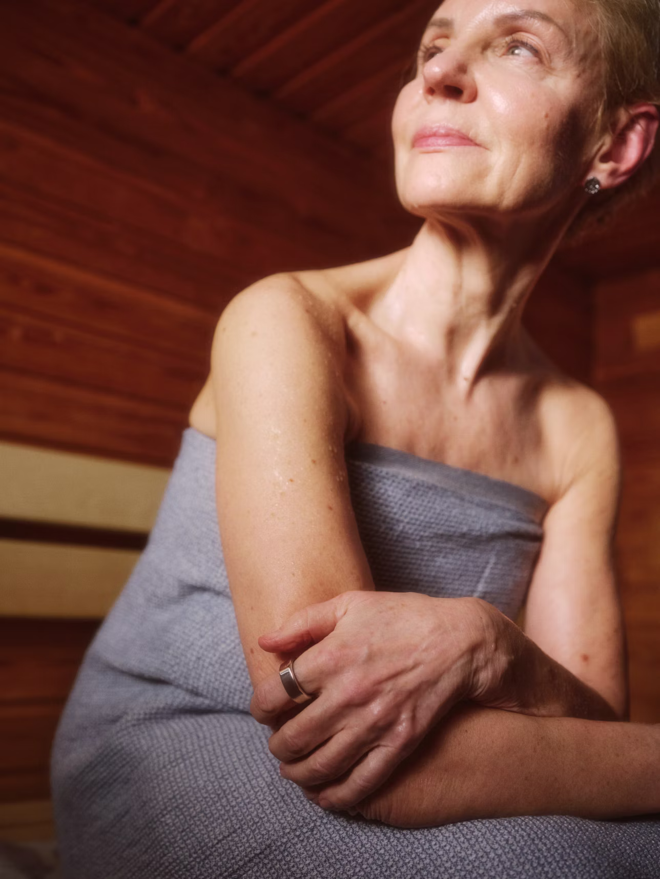Une femme assise dans un sauna, la KEORA Ring au doigt.