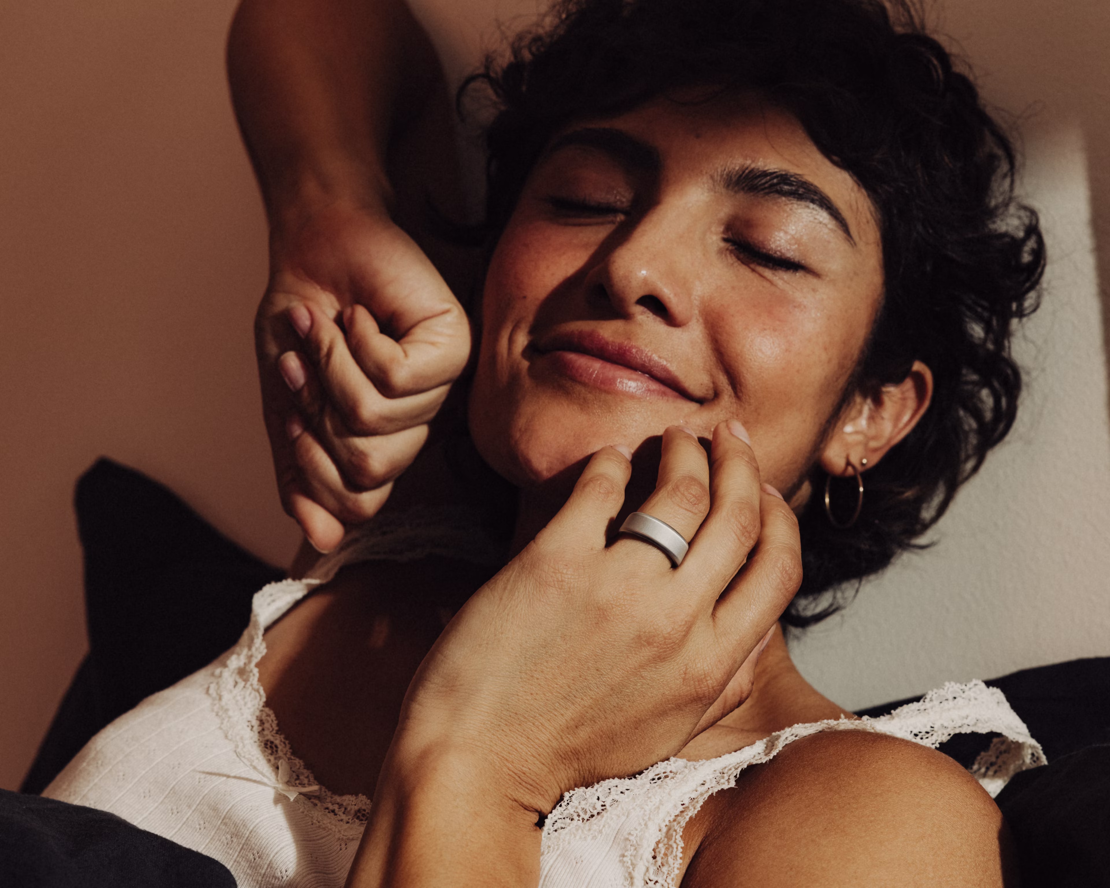 Gros plan sur une femme en train de s'étirer, la main près du visage, un KEORA Ring au doigt.