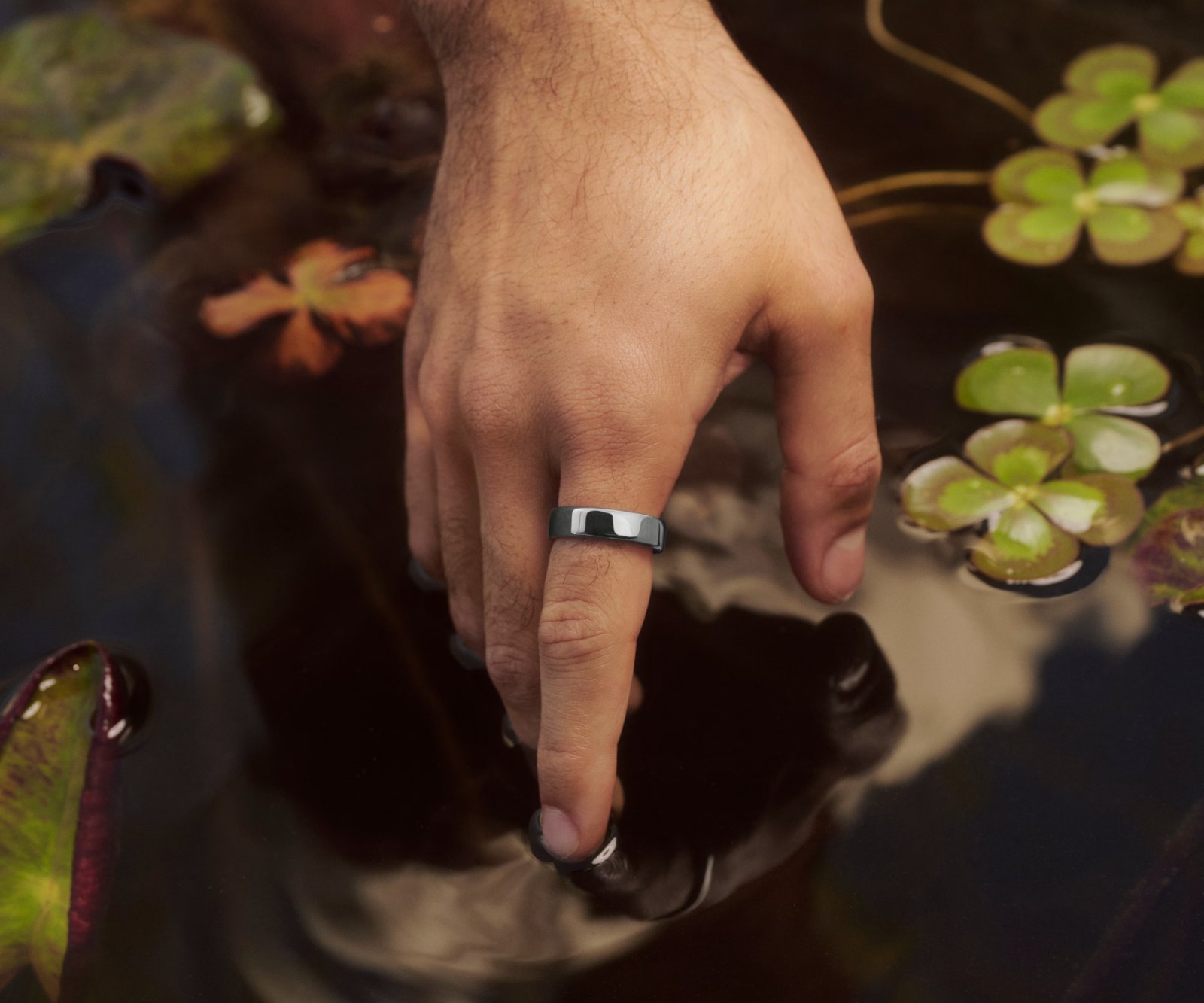 Gros plan sur la main d’une personne posée sur la surface d’un étang d’ornement, la KEORA Ring 6 Silver au doigt