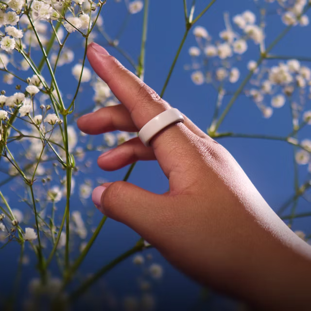 Gros plan sur la main d'une personne portant un KEORA Ring&nbsp;4 Ceramic Cloud au doigt