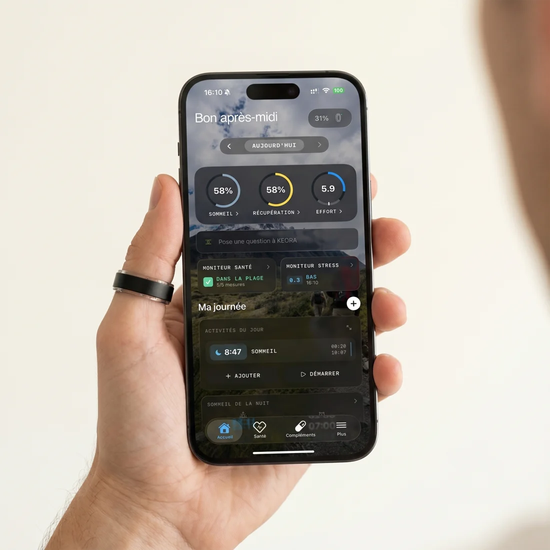 Main portant la bague KEORA tenant un iPhone qui affiche l'app KEORA