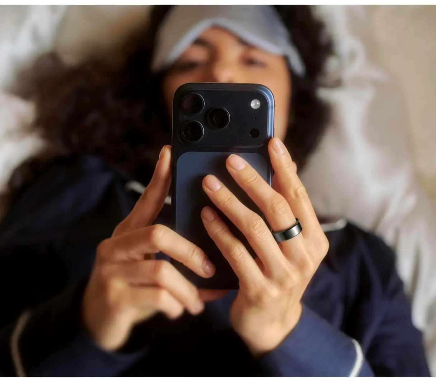 Une femme allongée qui regarde son téléphone, la KEORA Ring&nbsp;5 au doigt.